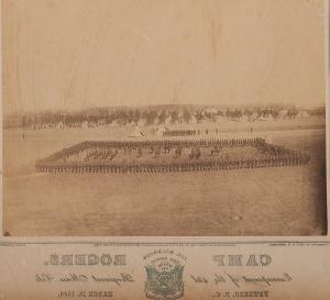 Sepia-toned image of a photograph showing people lined up in a rectangular shape. T在这里 are people in the middle of the rectangle. Some are on horseback. In the background are trees. 
