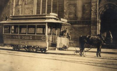 Reddish-brown photograph of a horse-drawn streetcar in front of a church